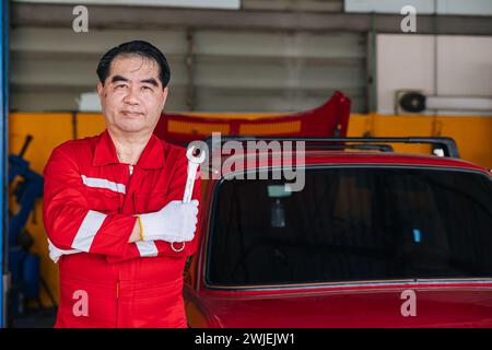 Felice senior professionista asiatico maschio meccanico officina lavoratore felice sostituire manutenzione auto servizio in officina auto Foto Stock