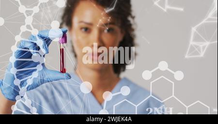 Immagine del filamento di dna e delle forme sopra una donna birazziale medico con provetta Foto Stock