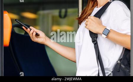Passeggero donna che paga il biglietto dell'autobus con il suo smartphone. Foto Stock