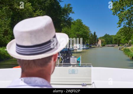 Crociera sul Canal du Midi, qui alla base nautica di Negra (sud della Francia). Uomo con un cappello che pilota una chiatta a noleggio. Il Canal du Midi è registe Foto Stock