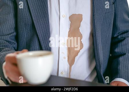 Un uomo irriconoscibile ha versato caffè o tè su una camicia bianca. concetto di colorazione della vita quotidiana. Foto Stock