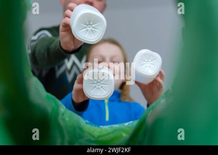 Visione ad angolo ridotto una famiglia di contenitori per lo smistamento delle bottiglie in plastica in casa. Smaltimento dei prodotti in bottiglia di latte. Foto Stock