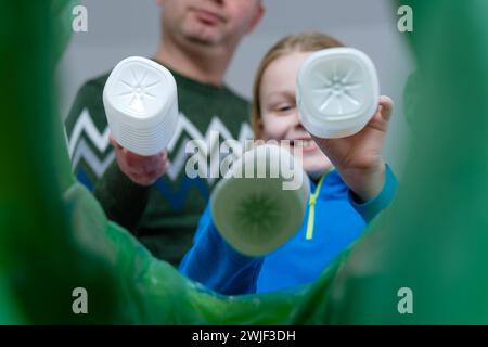 Visione ad angolo ridotto una famiglia di contenitori per lo smistamento delle bottiglie in plastica in casa. Smaltimento dei prodotti in bottiglia di latte. Sostenibilità e rispetto per l'ambiente Foto Stock