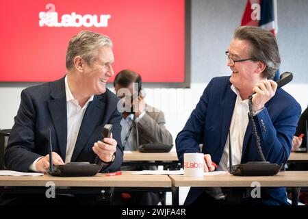 Il leader del lavoro Sir Keir Starmer (a sinistra) è affiancato dal musicista Feargal Sharkey che canvassola gli elettori telefonicamente per le elezioni suppletive di Wellingborough e Kingswood, presso il quartier generale laburista di Londra. Data foto: Giovedì 15 febbraio 2024. Foto Stock