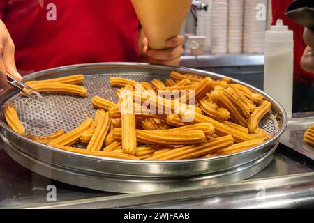 Negozio di churro, churros spagnoli e portoghesi. Pasticceria. Uomo che serve churros in negozio Foto Stock