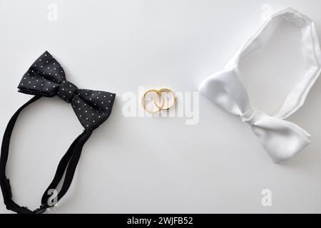 Concetto di matrimonio gay con papillon nero con pois di polka e bianco ai lati delle fedi nuziali al centro. Vista dall'alto. Foto Stock