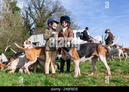 Arley, Worcestershire, Regno Unito. 15 febbraio 2024. Myla Mills di quattro anni e la sua amica Rosa, che sono fuori scuola durante un semestre, salutano i cani in un incontro sul prato della Albrighton and Woodland Hunt ad Arley, nel Worcestershire, in una giornata instagionalmente calda. Un prato si incontra normalmente precede un evento di caccia e si svolge su un terreno privato. Crediti: Peter Lopeman/Alamy Live News Foto Stock