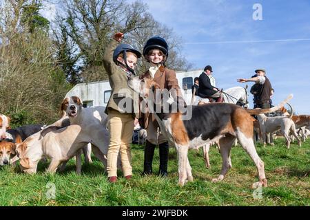 Arley, Worcestershire, Regno Unito. 15 febbraio 2024. Myla Mills di quattro anni e la sua amica Rosa, che sono fuori scuola durante un semestre, salutano i cani in un incontro sul prato della Albrighton and Woodland Hunt ad Arley, nel Worcestershire, in una giornata instagionalmente calda. Un prato si incontra normalmente precede un evento di caccia e si svolge su un terreno privato. Crediti: Peter Lopeman/Alamy Live News Foto Stock