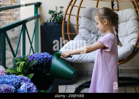 Una ragazza che annaffiava ortensie sul balcone Foto Stock