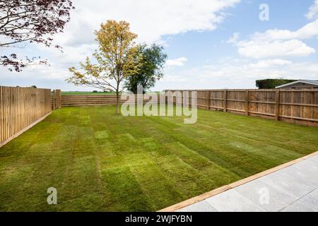 Cambridgeshire, Inghilterra - 1° maggio 2018: Prati di prati erbosi e giardini paesaggistici di nuovissime case con vista sulla campagna e patio Foto Stock