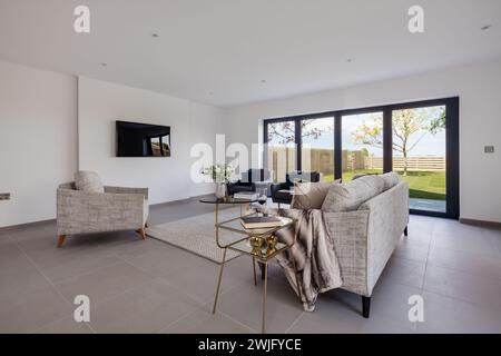 Cambridgeshire, Inghilterra - 1° maggio 2018: Salotto di lusso arredato in stile moderno, in una nuovissima casa vacante arredata con porte a due piazze per il patio e il giardino Foto Stock