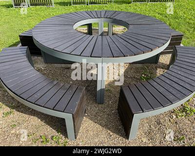 Un tavolo da picnic in legno con panche in un parco. Il tavolo è predisposto per un picnic, con una tovaglia rossa a scacchi, piatti, tazze e cibo. Ci sono due pe Foto Stock