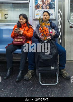 Coppia asiatica sulla metropolitana di New York con fiori rossi prima del Capodanno lunare venerdì 10 febbraio 2024. (© Richard B. Levine) Foto Stock