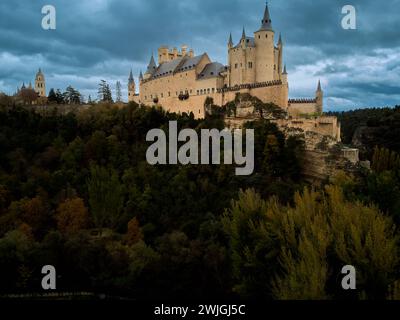 L'Alcazar di Segovia, un castello medievale con cielo nuvoloso e foresta Foto Stock