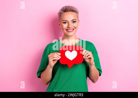 Foto di una bella ragazza che trasmette le braccia sorridenti, con carta come una scheda di notifica isolata su sfondo di colore rosa Foto Stock