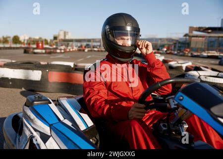 Il conducente si stacca dal casco protettivo mentre è seduto all'auto da corsa di kart Foto Stock