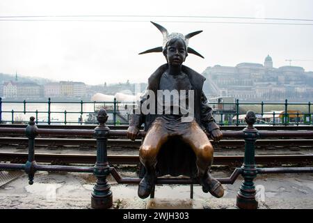 La statuetta originale di 50 cm della piccola Principessa Kiskirálylány seduta sulle ringhiere del lungomare del Danubio a Budapest, Ungheria Foto Stock