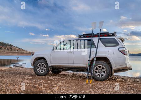 Loveland, CO, USA - 13 febbraio 2024: Toyota 4Runner SUV con guscio di canottaggio e remi da scuoiamento su una riva del lago Carter nel Colorado settentrionale. Foto Stock