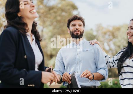 Gli studenti universitari scambiano conoscenze e lavorano insieme a un progetto di facoltà in un parco soleggiato, cercando di ottenere il successo accademico. Foto Stock