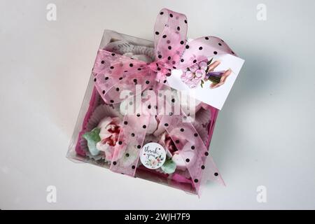 Fiori di Zephyr. Confezione regalo con tulipani e fiocchi rosa su sfondo bianco. Tulipani dai marshmallow. zephyr fatto in casa. Foto Stock