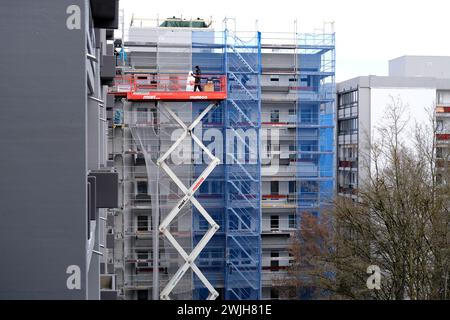 I lavoratori riparano casa, montano l'isolamento delle solette, salgono sulla macchina idraulica di sollevamento a forbice, concetto di riparazione e isolamento delle facciate degli edifici Foto Stock