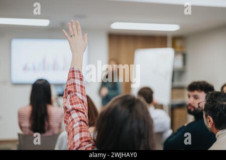 Allievo impegnato che alzava la mano durante un seminario aziendale in ufficio Foto Stock