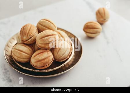 Biscotti fatti in casa a forma di noce con latte condensato bollito su un tavolo in marmo bianco Foto Stock