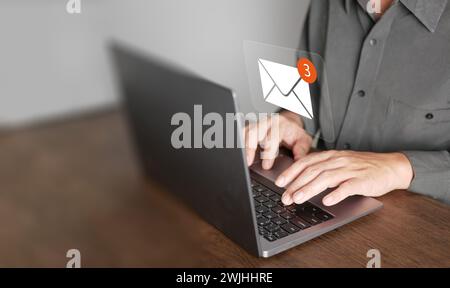 E-mail o posta elettronica. Un uomo utilizza un computer portatile per inviare e ricevere messaggi online con icone di posta elettronica, marketing e newslette Foto Stock