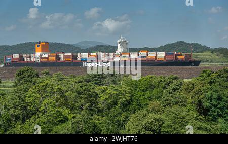 Canale di Panama, Panama - 24 luglio 2023: Primo piano, nave container Hapag-Lloyd nella nuova chiusa di Pedro Miguel sotto il paesaggio blu dietro alberi verdi. Contenitore Foto Stock