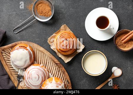 Panini con panna, bastoncini di cannella e tazza di caffè su sfondo grunge nero Foto Stock