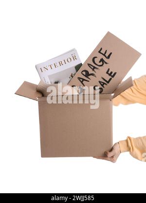 Mani femminili che tengono in mano scatola di oggetti indesiderati e cartone con VENDITA IN GARAGE DI testo su sfondo bianco Foto Stock