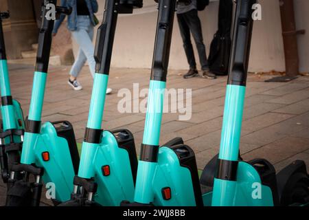 Allineato sul marciapiede della città, questa serie di scooter elettrici senza porto è pronta a trasportare gli esploratori urbani per le strade d'Europa. Un simbolo di m. Foto Stock