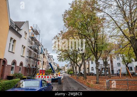 Immagine di un quartiere residenziale di Colonia, in Germania, con auto parcheggiate in una strada deserta, edifici a più piani e progetti di ristrutturazione in corso Foto Stock