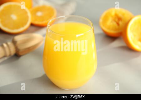 Succo appena fatto, arance e alesatore sul tavolo, primo piano Foto Stock