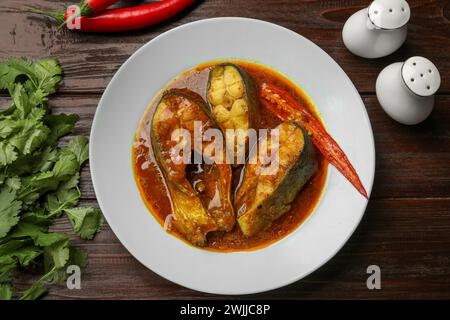 Gustoso curry di pesce servito su un tavolo di legno, piatto. Cucina indiana Foto Stock