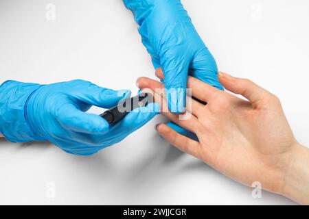 Diabete. test del glucosio. Medico che usa la lancetta su sfondo bianco, primo piano Foto Stock