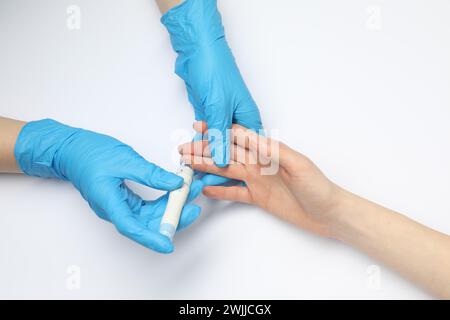 Diabete. test del glucosio. Medico che utilizza una penna a lancetta su sfondo bianco, vista dall'alto Foto Stock