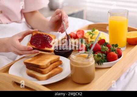 Donna che fa una gustosa colazione a letto, primo piano Foto Stock