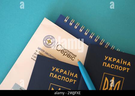 KIEV, UCRAINA - 27 NOVEMBRE 2023 logo del servizio passaporti con passaporto ucraino internazionale e penna sul tavolo Foto Stock