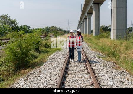 Due persone sono in piedi sui binari della ferrovia e guardano insieme il computer portatile. Foto Stock