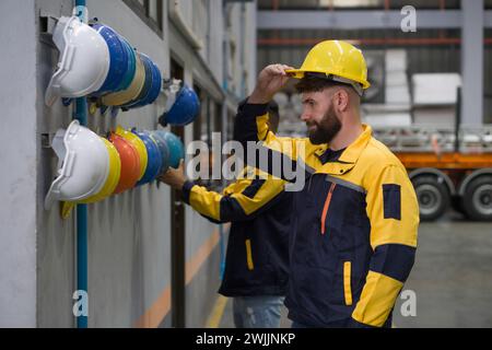 Due persone lavorano in una fabbrica. Indossano elmetto di costruzione sulla testa per motivi di sicurezza. Concetto di sicurezza sul lavoro. Industria edile. Foto Stock