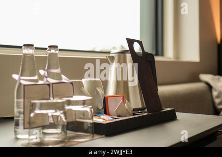 Un tavolo in una camera d'hotel con un vassoio di bicchieri da acqua e una bottiglia d'acqua a disposizione degli ospiti. Foto Stock
