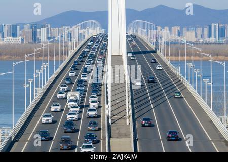 NANJING, CINA - 16 FEBBRAIO 2024 - Un gran numero di veicoli guida lentamente sul ponte del fiume Yangtze di Nanjing Jiangxinzhou, prov. Jiangsu Foto Stock