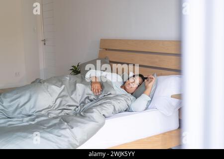 Una giovane donna birazziale di grandi dimensioni gode di una rilassante mattinata a letto a casa Foto Stock
