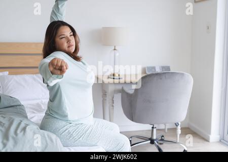Giovane donna birazziale più grande si allunga dopo essersi svegliata nella sua camera da letto Foto Stock