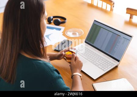 Una giovane donna birazziale di grandi dimensioni lavora in un ufficio domestico Foto Stock