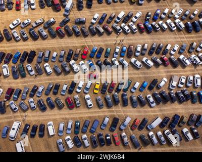 Vista dall'alto che cattura la pienezza di un parcheggio con numerosi veicoli organizzati in file. Foto Stock