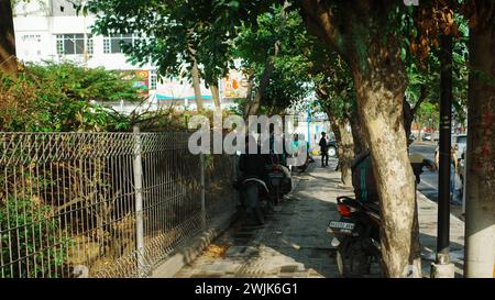 Sotto i cieli soleggiati della città di Medan, un operaio Gojek naviga lungo la strada pedonale, incarnando la mobilità urbana e la vitalità Foto Stock