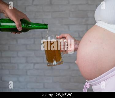 Un uomo che versa birra per una donna incinta. Foto Stock