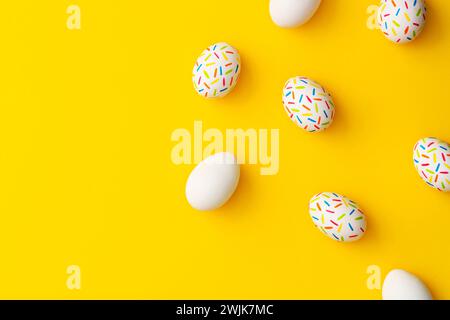 Cospargere le uova di pasqua colorate su sfondo giallo. Direttamente sopra l'immagine del piano d'esame. Foto Stock